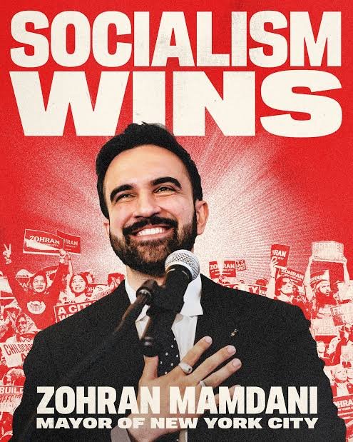 Zohran Mamdani, Mayor of New York City, smiling at a microphone, on a red poster that reads "Socialism wins".